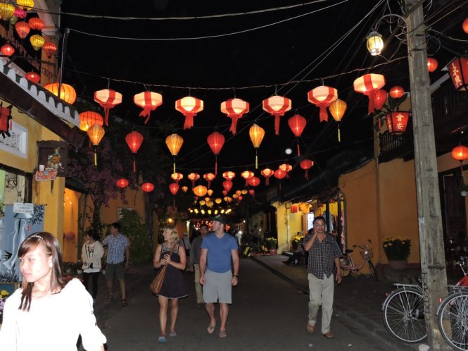 Foreigners are shown marvelling at Hoi An Ancient Town's charm in the dim light of colorful lanterns. Photo: Tuoi Tre